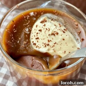 A stunning close-up of a chocolate budino in a glass, topped with a delicate swirl of creme fraiche and a sprinkle of flaky sea salt, highlighting its rich texture.