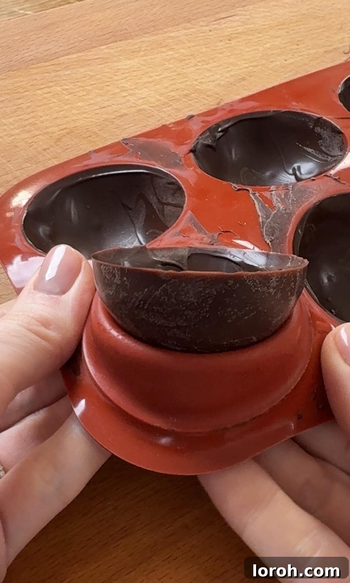 Removing a hardened chocolate semi-sphere from a silicone mould.