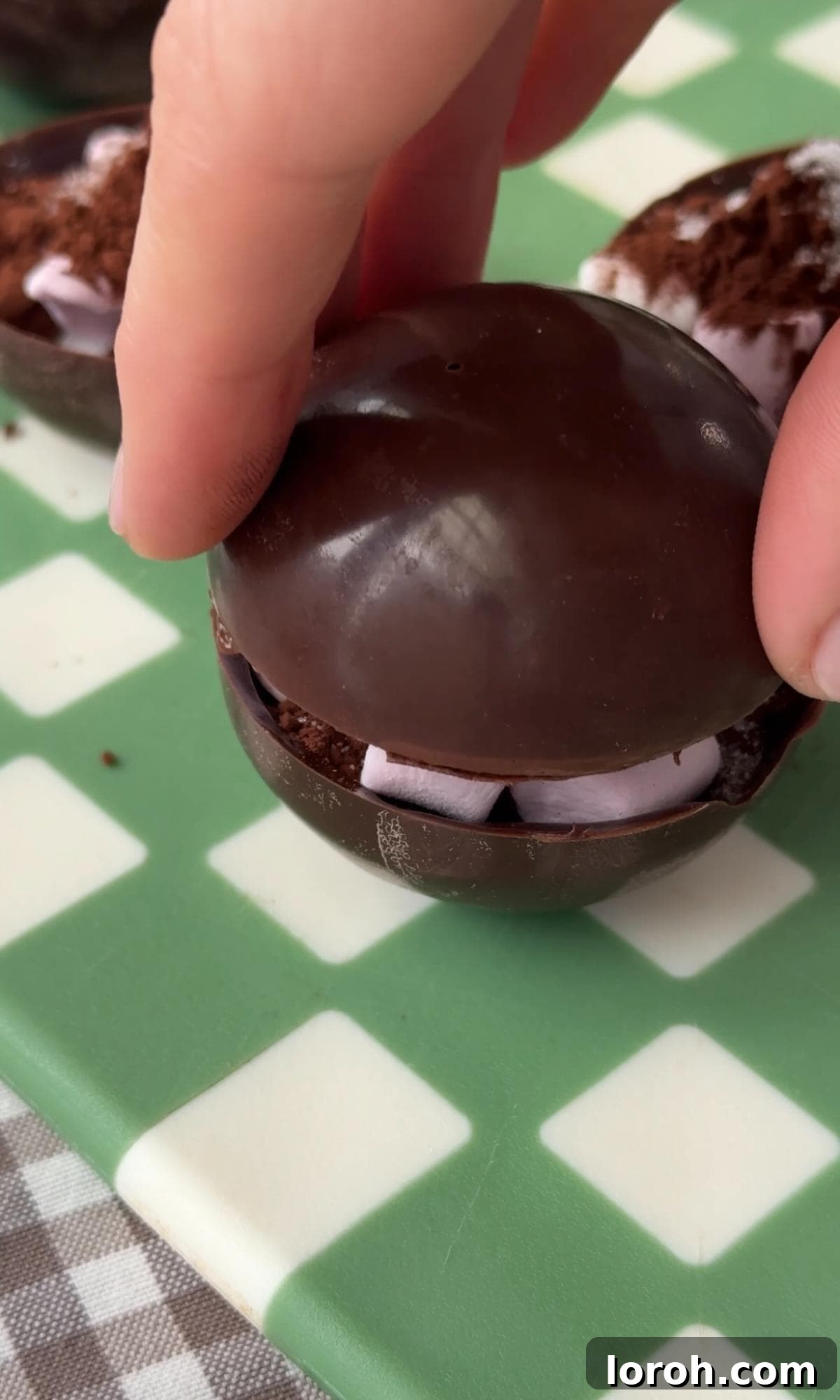Sealing two chocolate semi-spheres together to form a hot chocolate bomb.