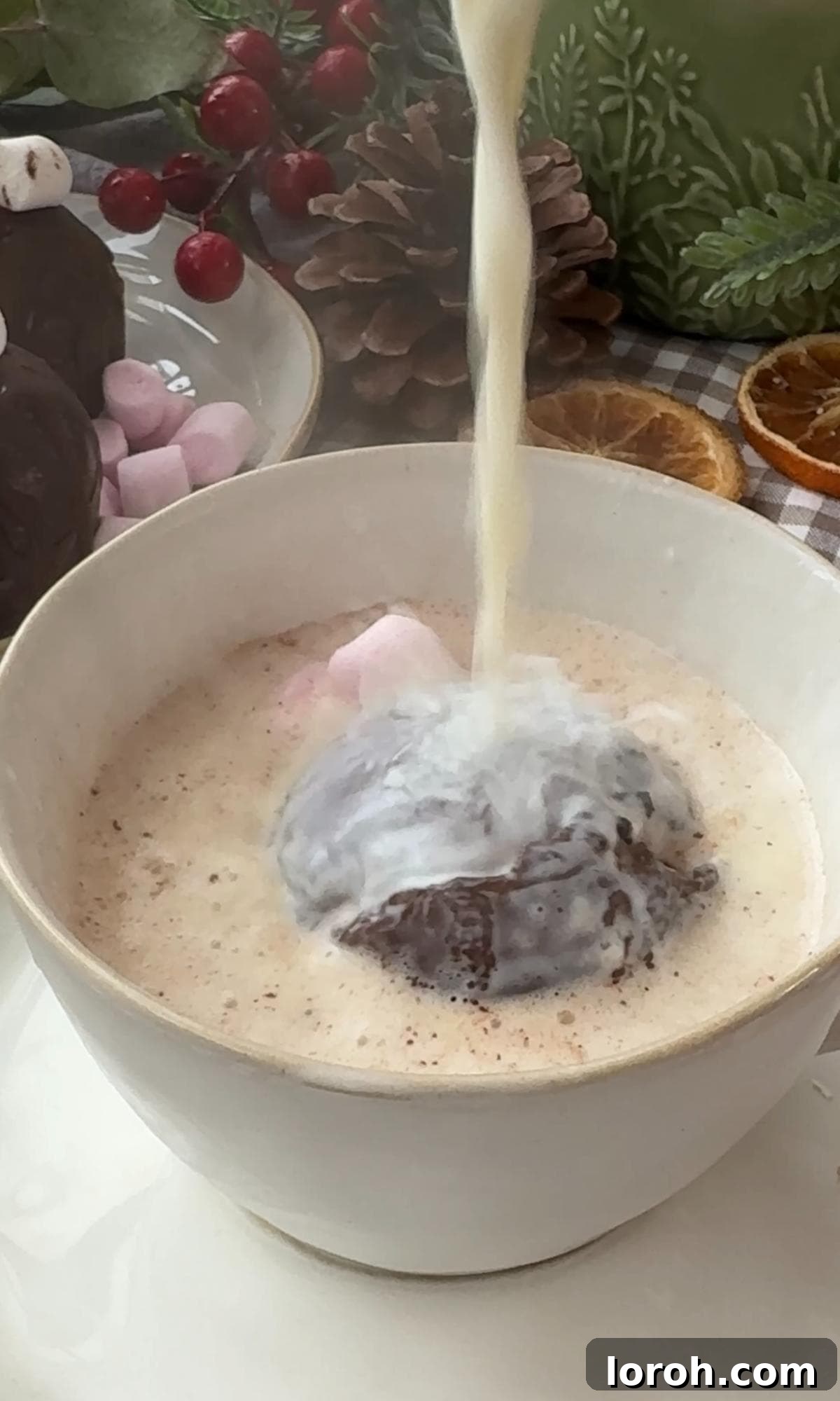 A hot chocolate bomb placed in a mug, with hot milk being poured over it.