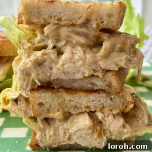 A perfectly halved Coronation Chicken sandwich showcasing the creamy curried chicken filling and crisp lettuce.