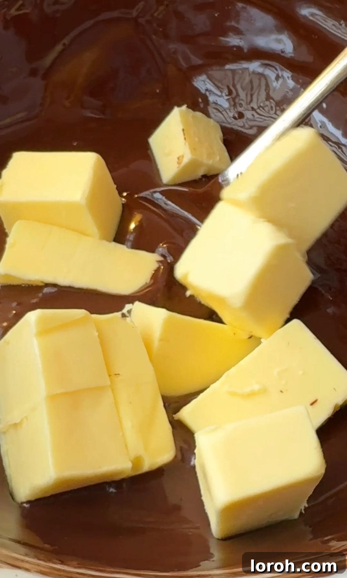 Decadent Chocolate Salami 4 adding butter to melted chocolate in a heatproof bowl.