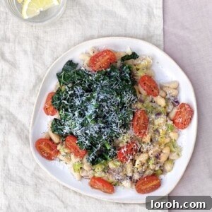 A vibrant bowl of creamy cannellini beans 'risotto' topped with roasted tomatoes, cavolo nero, and grated parmesan.