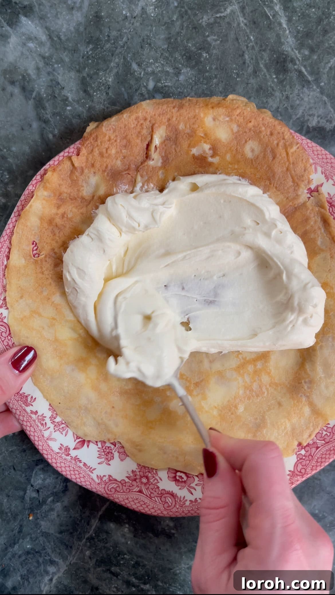 spreading mascarpone cream on a soaked pancake.
