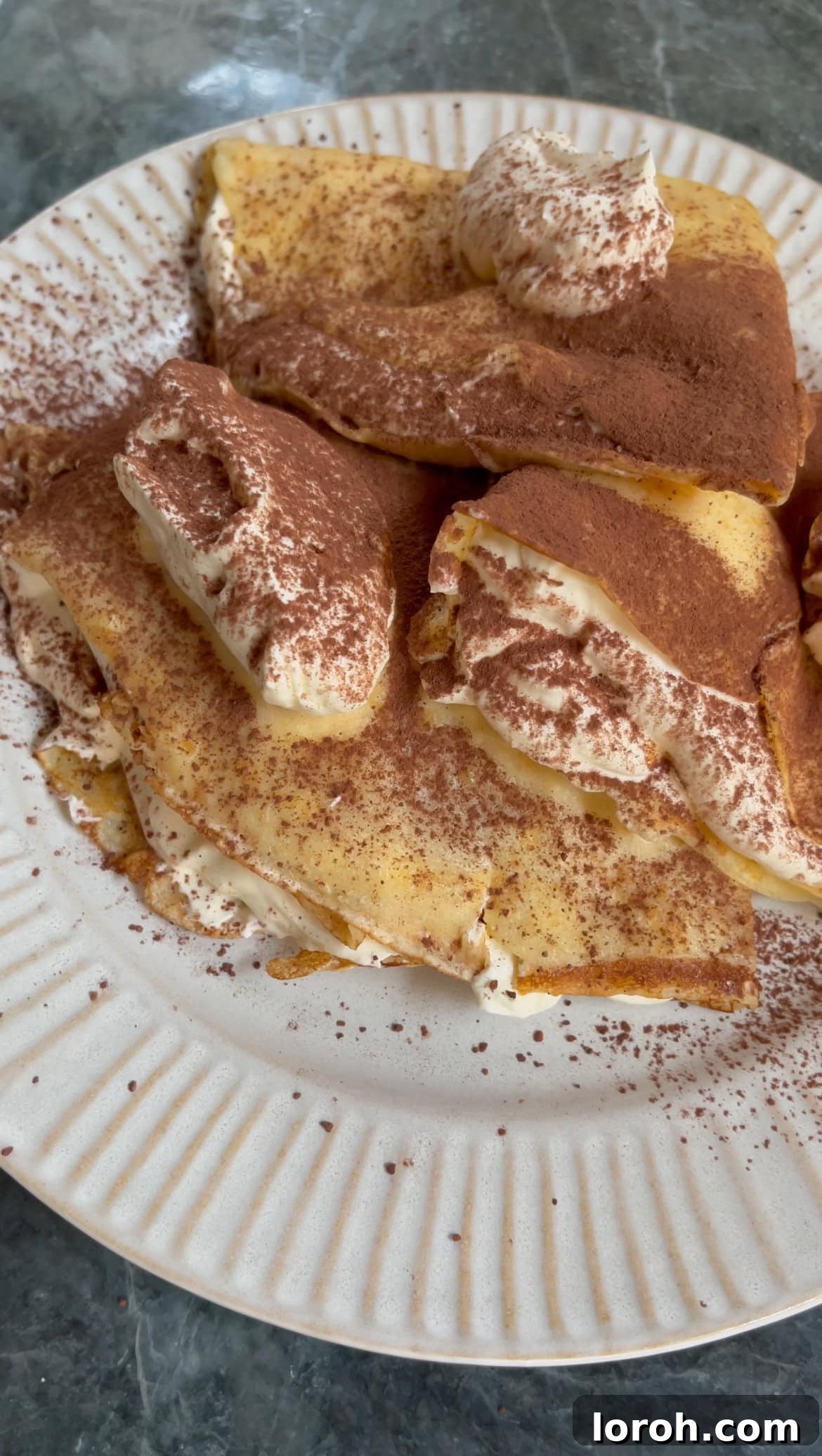 dusting folded pancakes with cocoa powder.