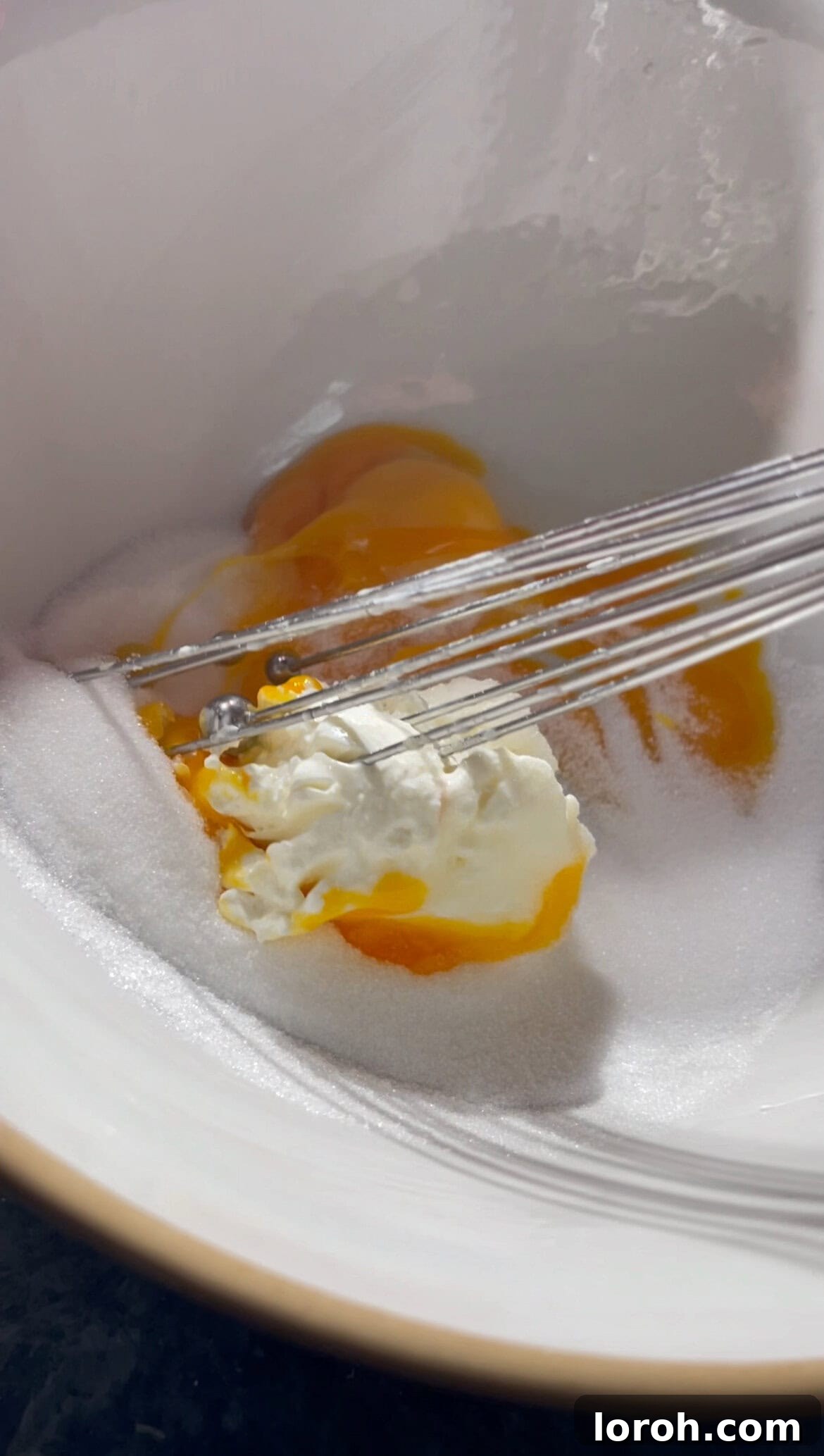 whisking mascarpone, egg yolks, and sugar in a bowl.