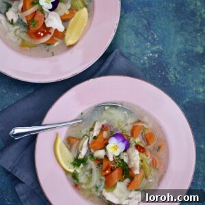 A steaming bowl of comforting chicken soup garnished with fresh parsley and a lemon wedge, ready to be enjoyed.