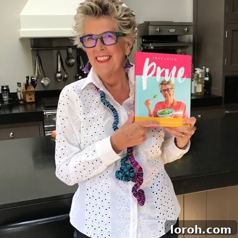 Prue Leith smiling warmly, dressed in vibrant clothing, emblematic of her cheerful personality and culinary flair.