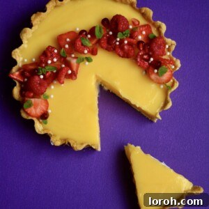 Delicious Easy Lemon Tart with Fresh Berries and Mint, served on a white platter.
