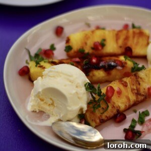 Delicious grilled chili pineapple slices served with creamy coconut ice cream and pomegranate seeds