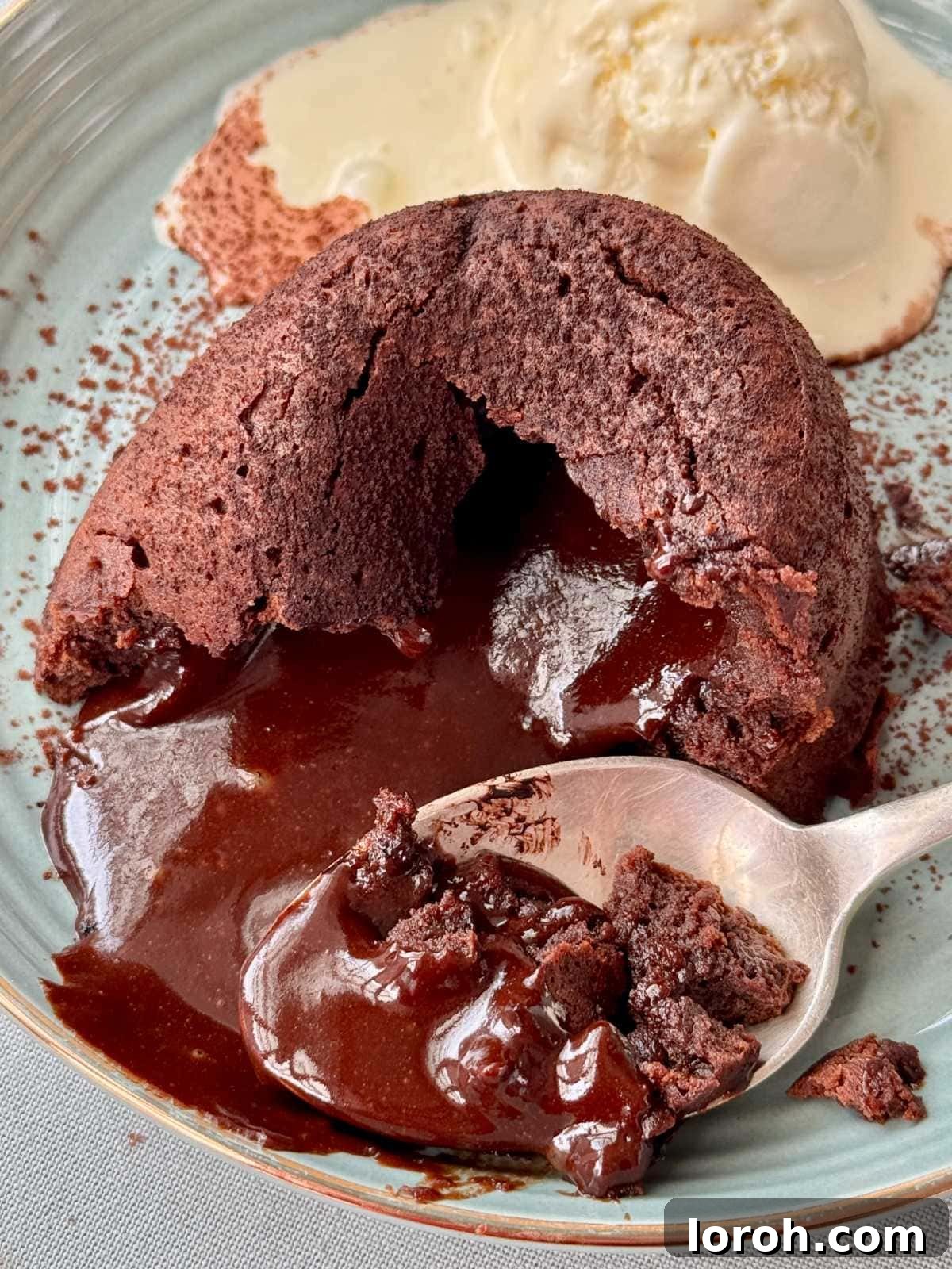 Molten Lava Chocolate Pudding 3 A spoon breaking into a melt-in-the-middle chocolate pudding, revealing a rich, dark molten center.