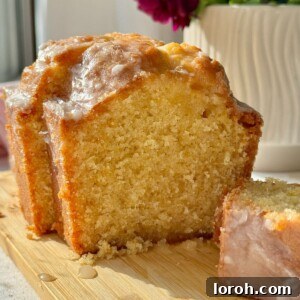 A delightful lemon loaf cake presented on a rustic wooden board, ready to be sliced.