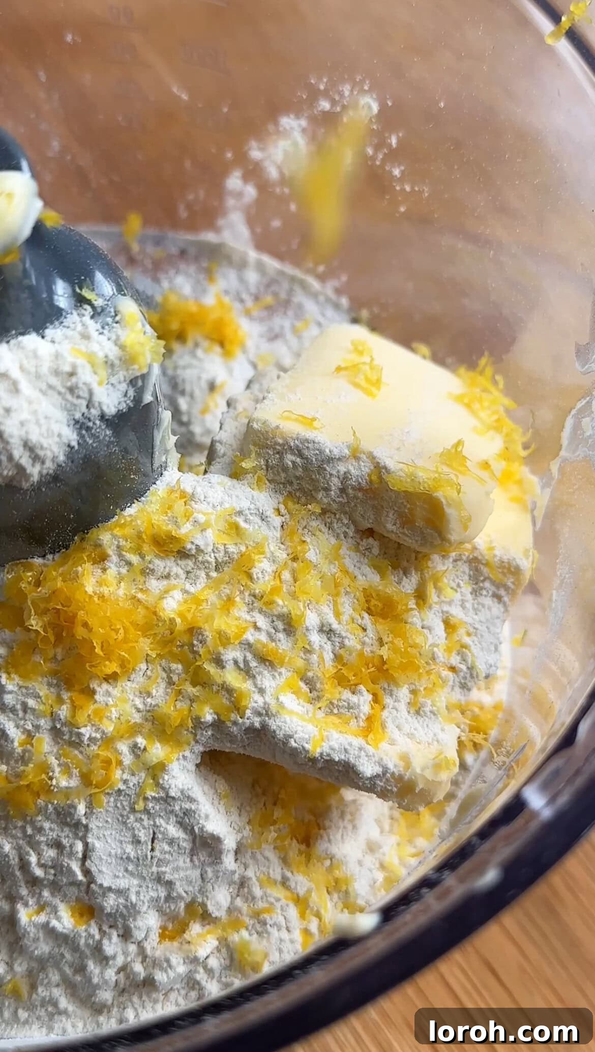 Sunshine Lemon Loaf 5 Fresh lemon zest being grated directly into the food processor with dry ingredients.