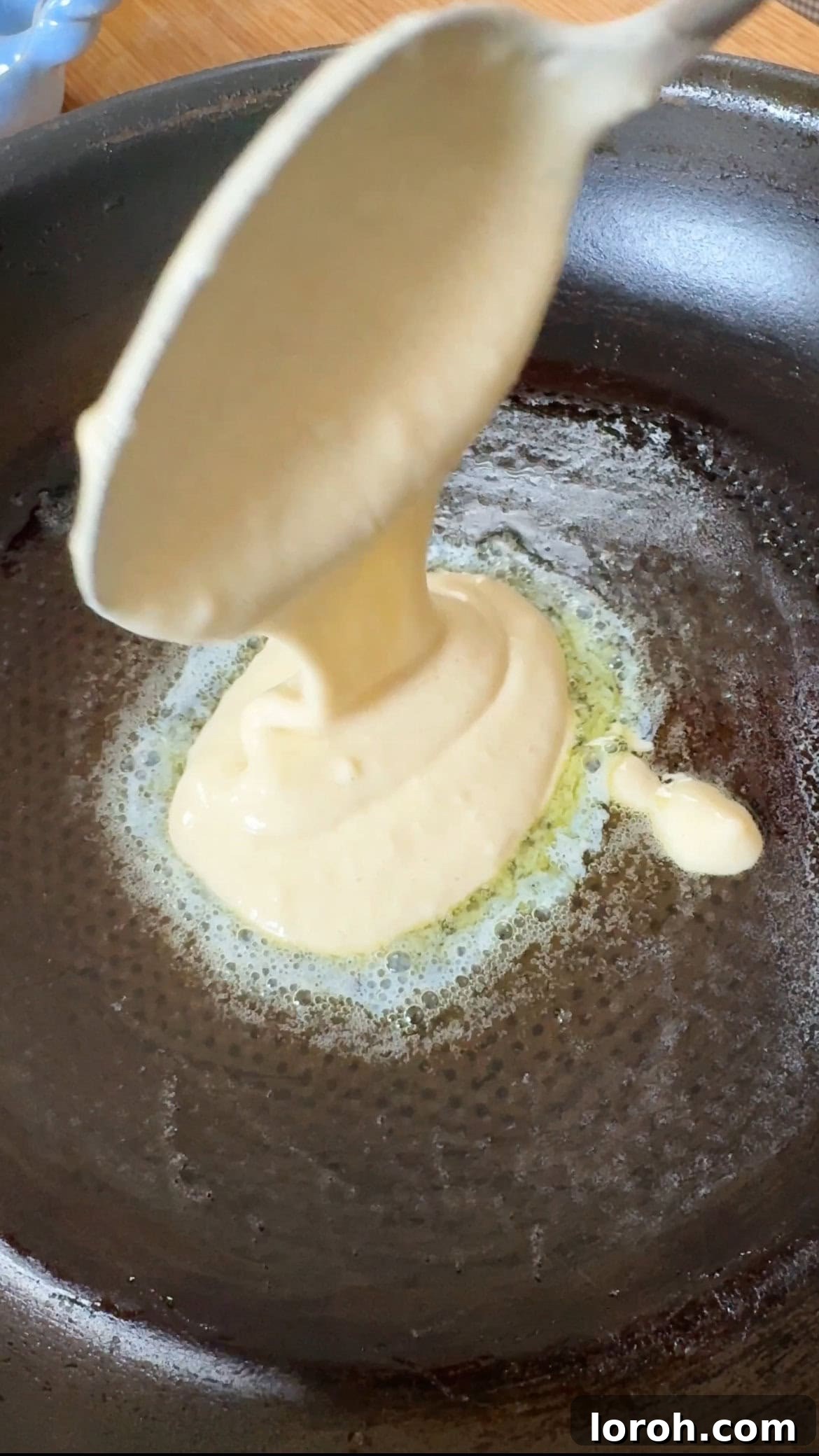 Effortless Fluffy Pancakes Without Baking Powder 5 Two small pancakes cooking in a nonstick pan, sizzling gently.
