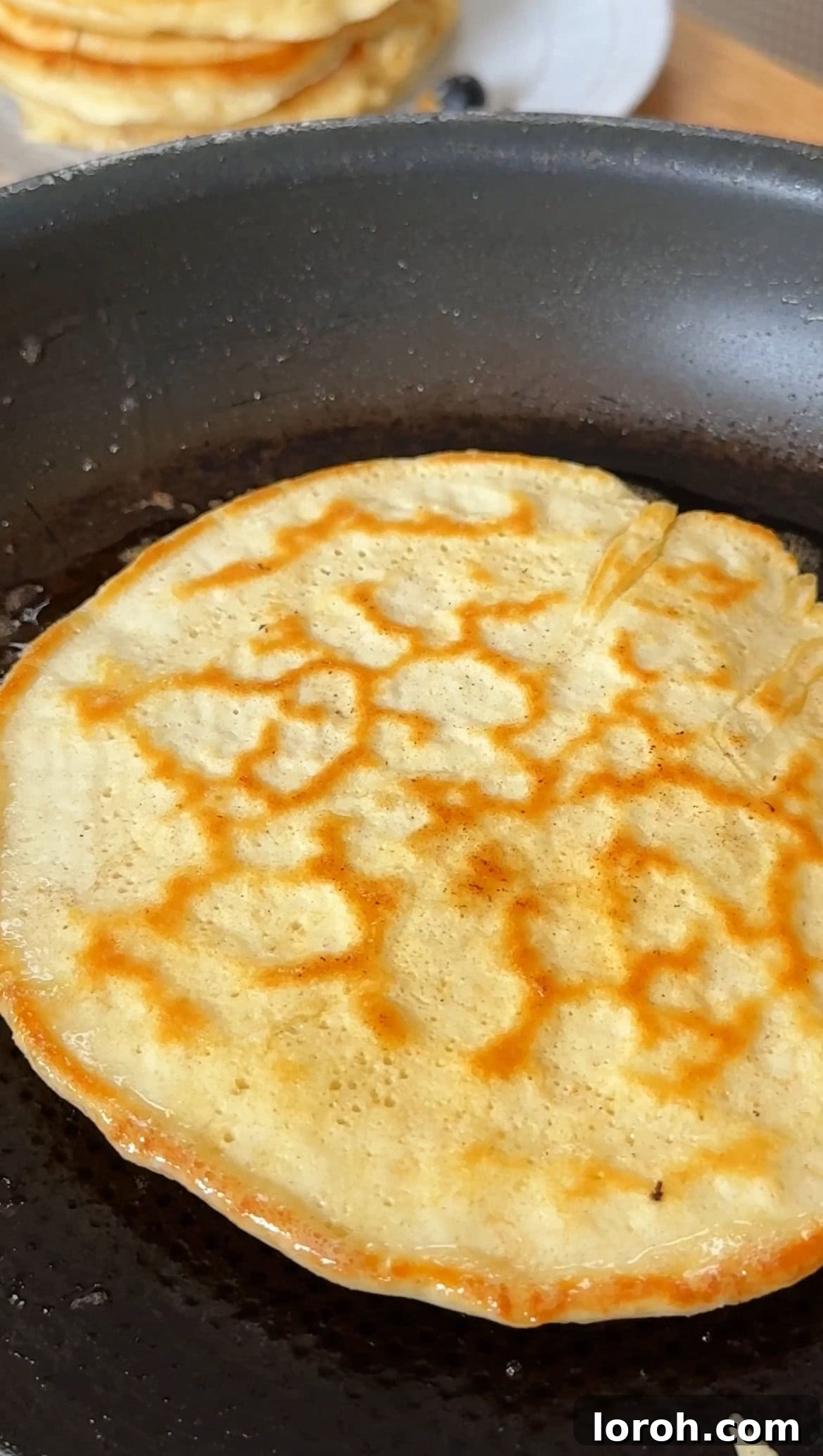 Effortless Fluffy Pancakes Without Baking Powder 7 A spatula flipping a golden pancake in a hot pan.