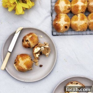 Effortless Hot Cross Buns 2 Freshly baked golden brown hot cross buns with perfectly piped white crosses, arranged on a baking sheet.