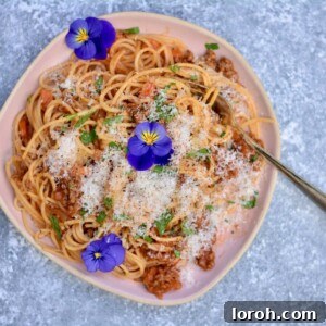 Rhiannon Lambert's Signature Spaghetti Bolognese 2 A mouthwatering bowl of classic spaghetti bolognese, generously topped with grated Parmesan cheese and fresh parsley.