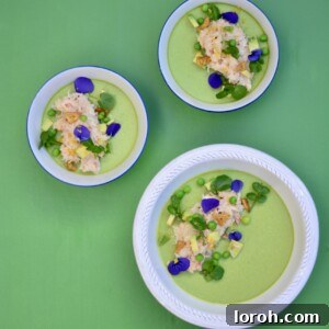 Vibrant green pea pannacotta topped with fresh crab meat and diced avocado, elegantly presented in a shallow bowl.