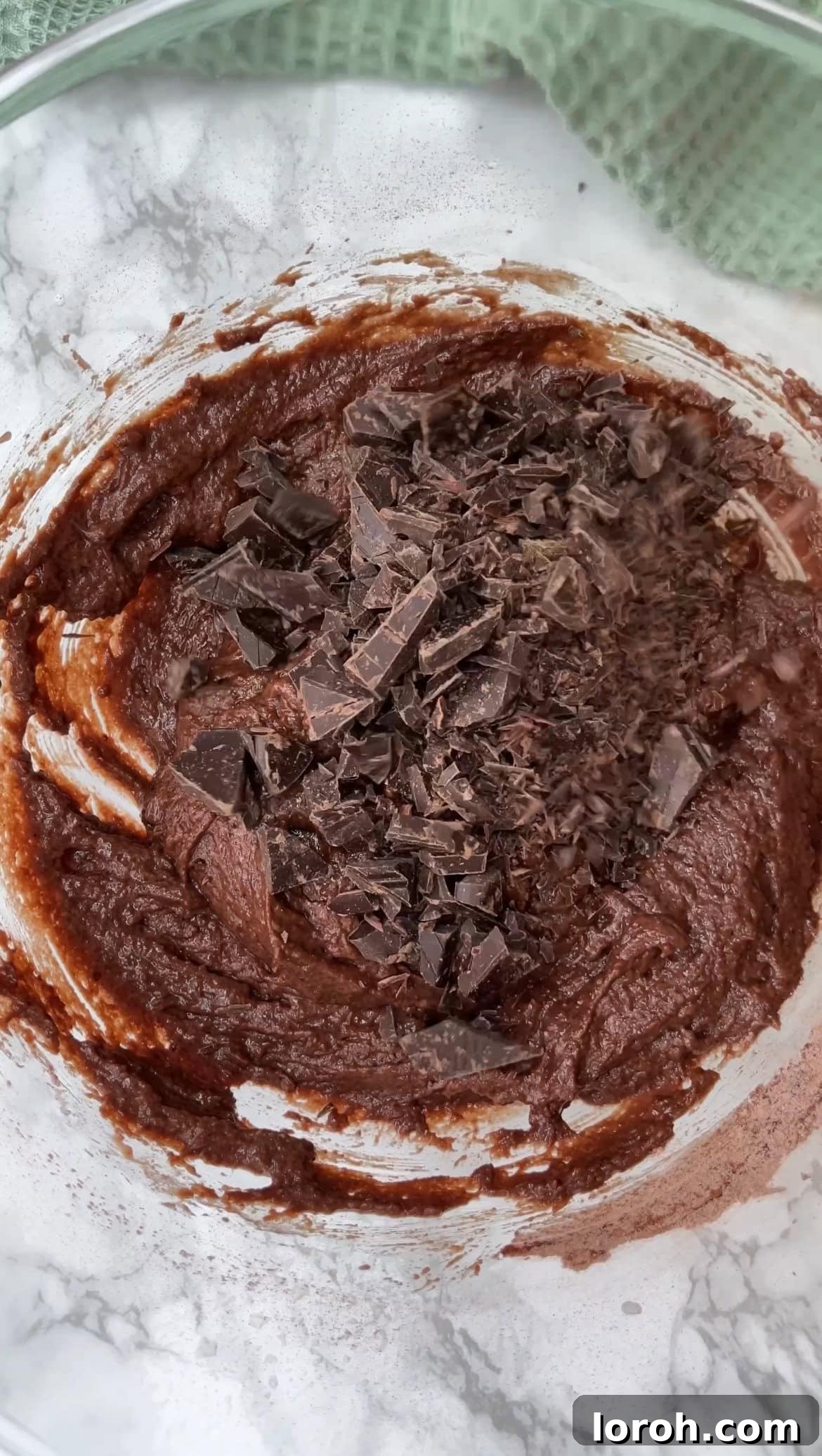 Step three: Gently stirring dark chocolate chunks into the muffin batter.