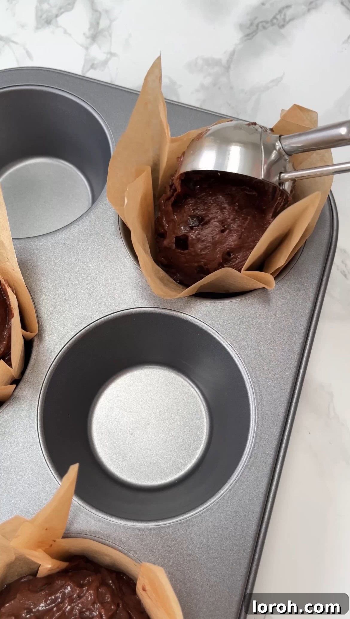 SCOOPING MUFFIN BATTER INTO A LINED MUFFIN TIN