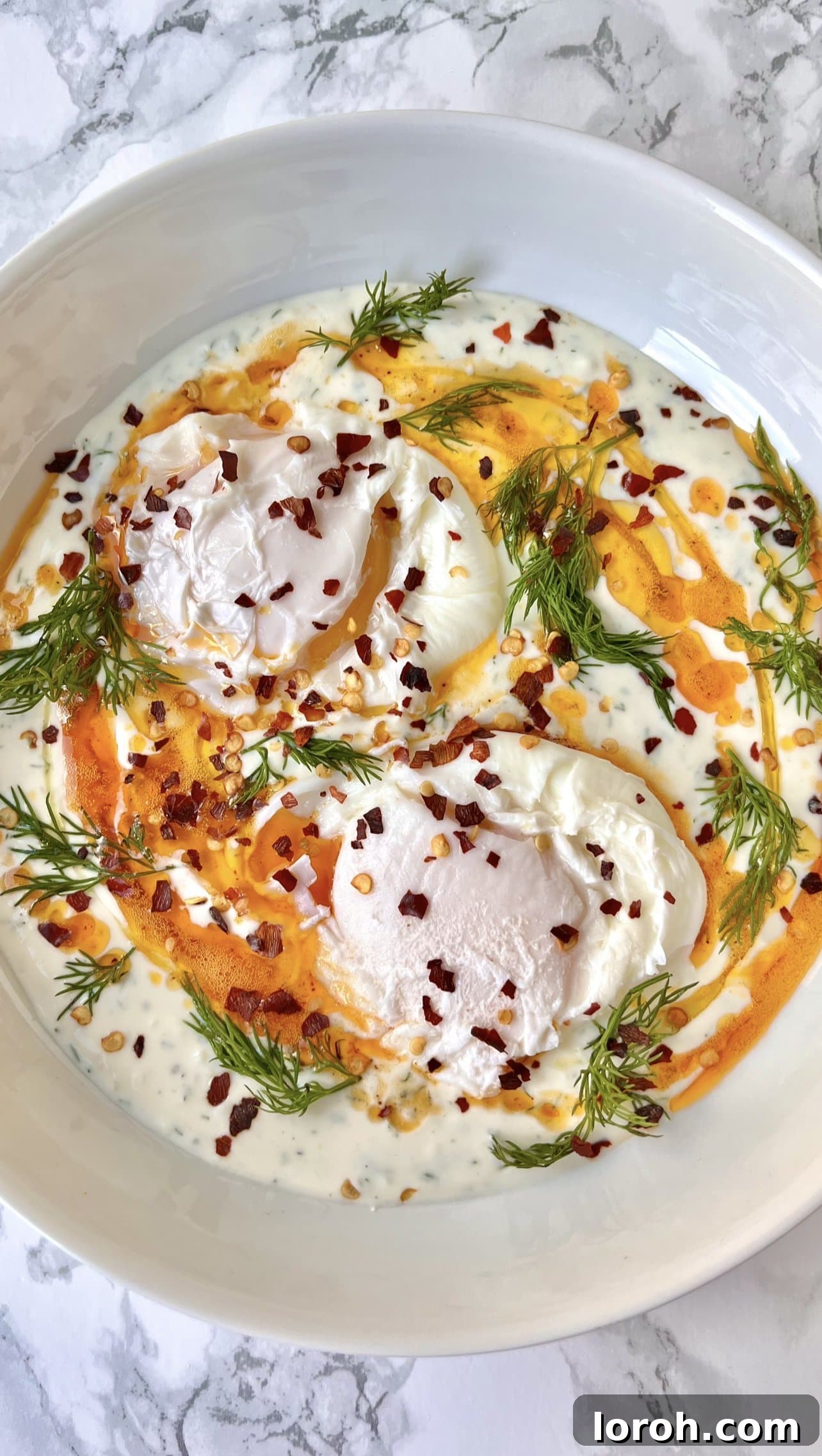 Delicious Turkish Eggs with spiced butter and fresh dill, ready to be served on creamy yogurt