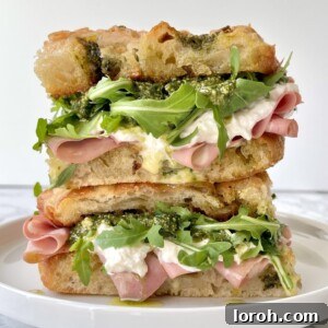 mortadella burrata sandwich with rocket, pesto, stacked on a plate