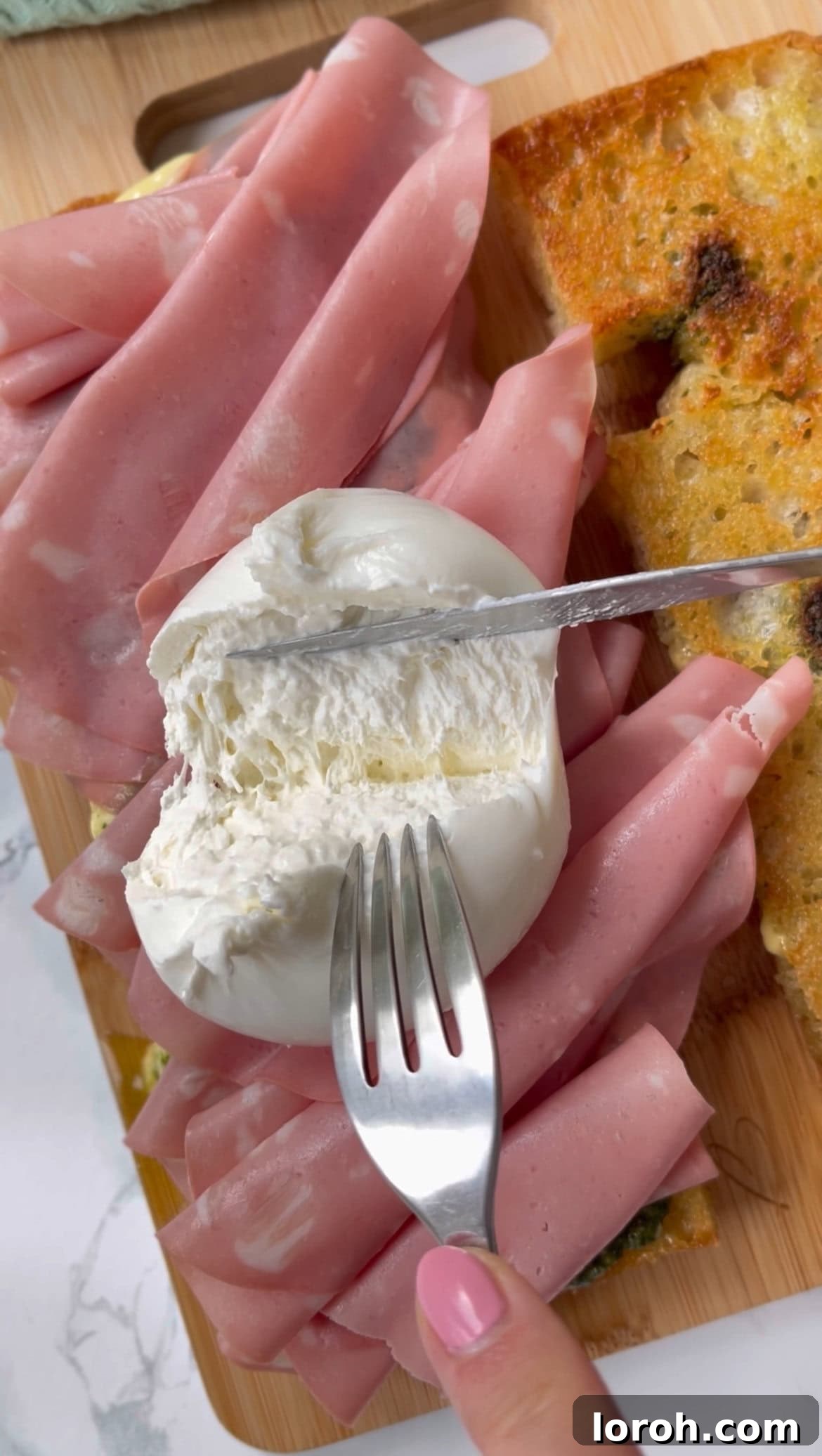 adding mortadella curls and burrata to focaccia sandwich