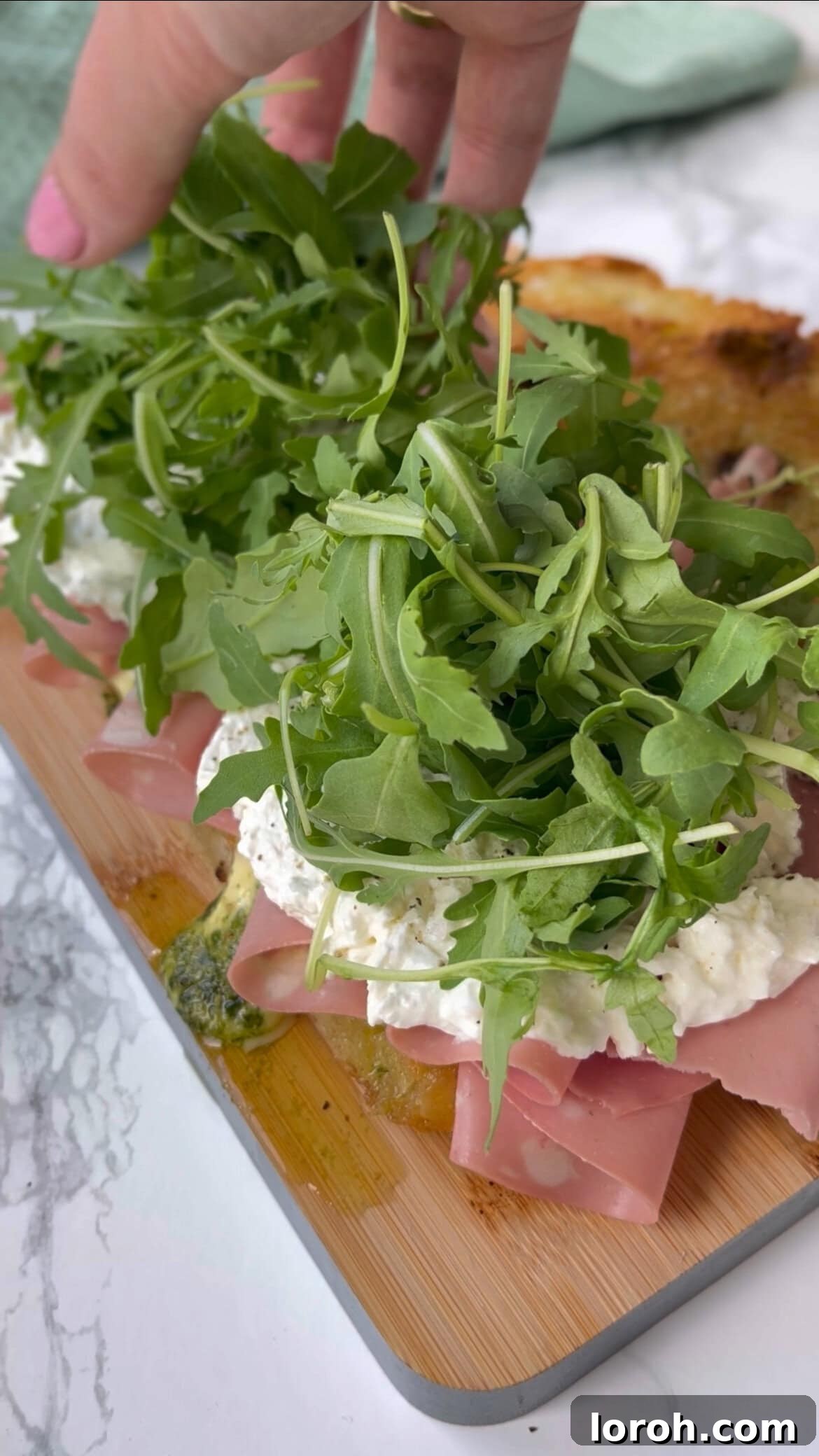 adding rocket (arugula) to mortadella burrata sandwich