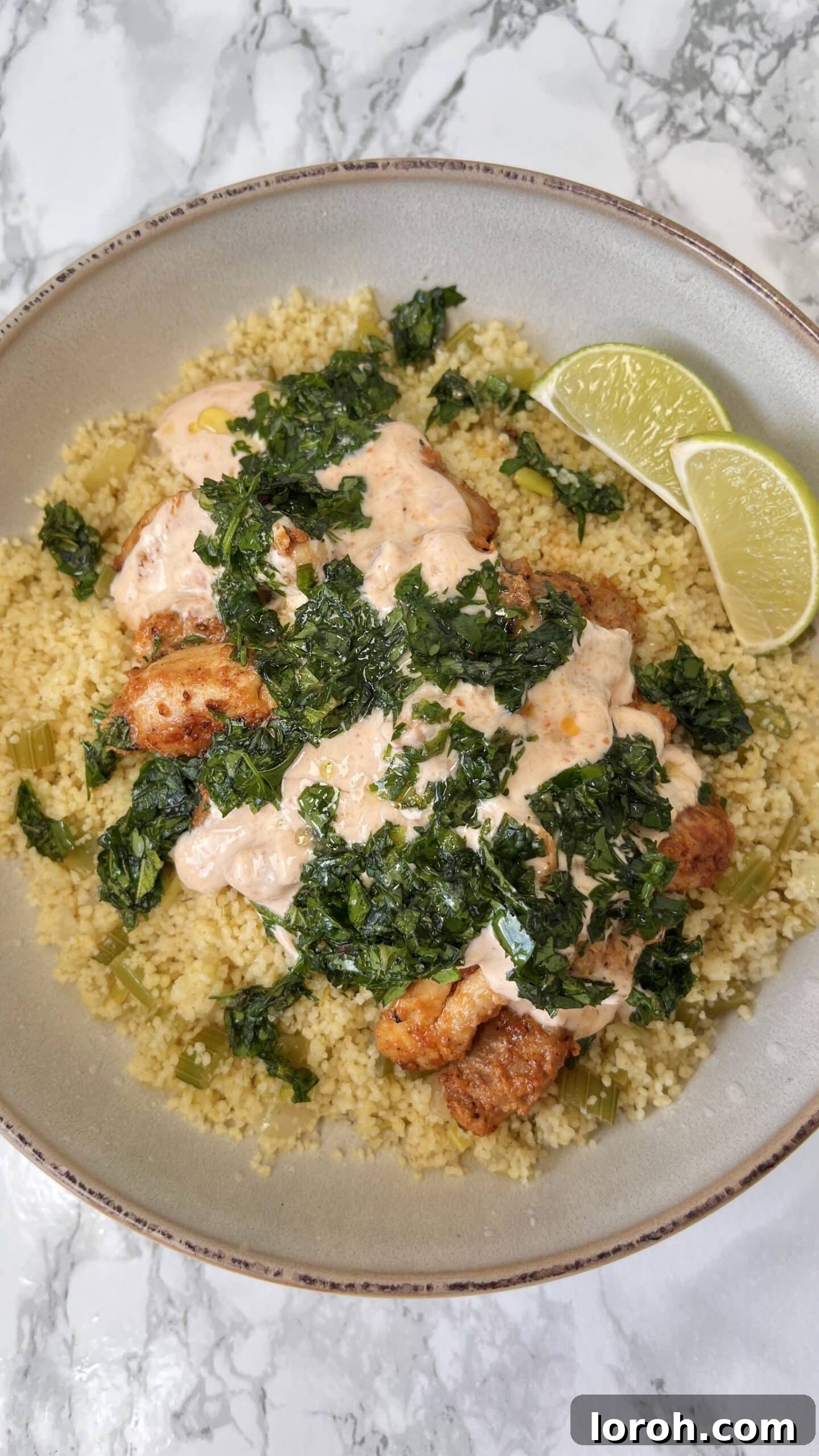 Fiery Harissa Chicken and Speedy Couscous 2 harissa chicken and couscous served with fresh herbs and lemon wedges.