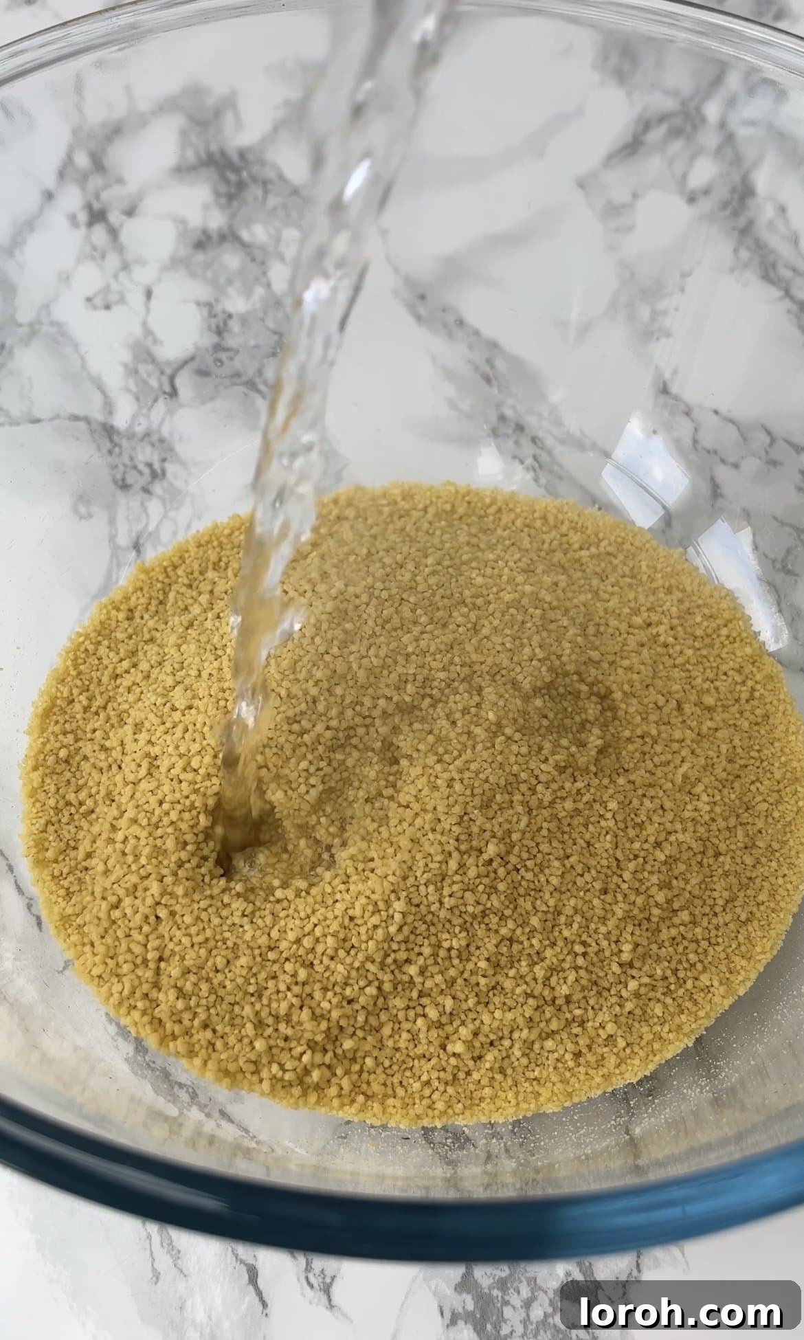 Fiery Harissa Chicken and Speedy Couscous 5 Boiling water being poured over dry couscous in a large bowl, covered to absorb.
