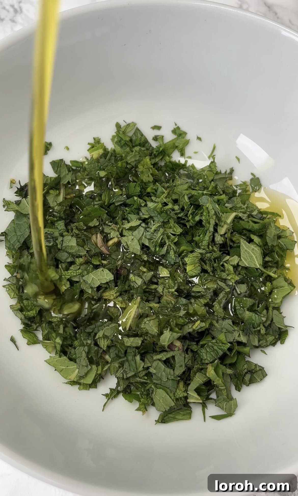 Fiery Harissa Chicken and Speedy Couscous 10 Finely chopped parsley and mint being mixed with olive oil and salt to create a herby drizzle.