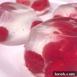 Elderflower and Raspberry Jellies served in elegant glasses, garnished with fresh raspberries and a sprig of mint.