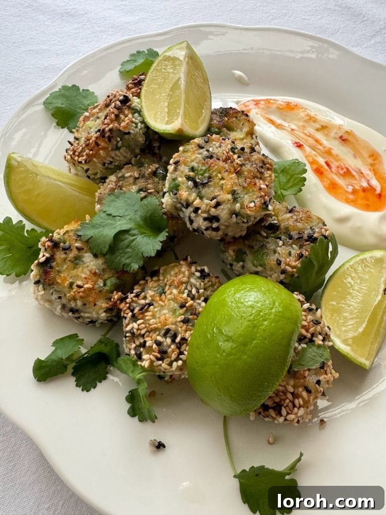 Plate of sesame seed coated fish cakes with fresh lime wedges.