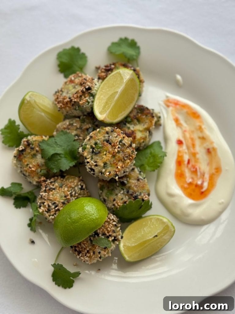 White plate of sesame seed coated fish cakes with lime wedges, fresh coriander and a creaky sweet chilli dip.