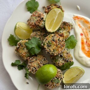 Plate of Thai Fish Cakes coated in sesame seeds served with spicy mayo, lime wedges and fresh coriander.