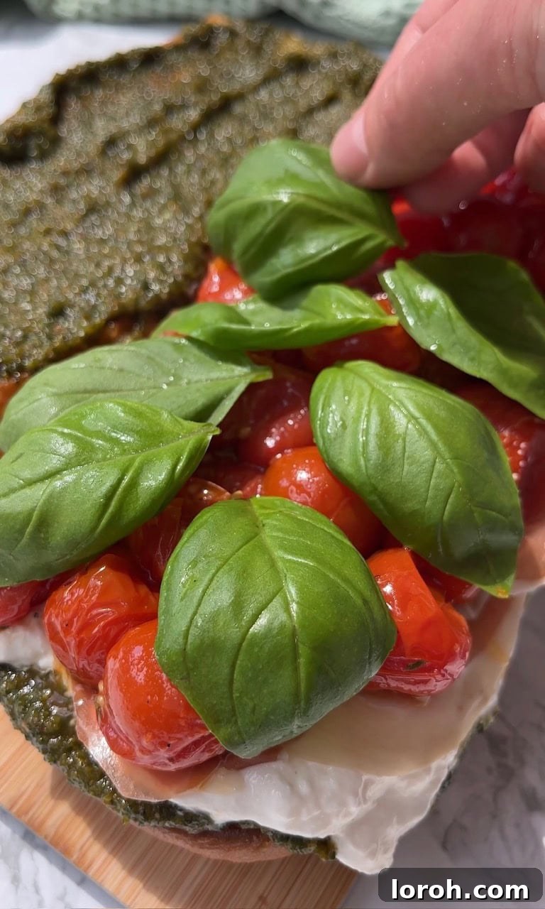 Burrata Caprese Prosciutto Sandwich Drizzled with Pistachio Pesto 11 Completing the sandwich with roasted tomatoes and fresh basil leaves.