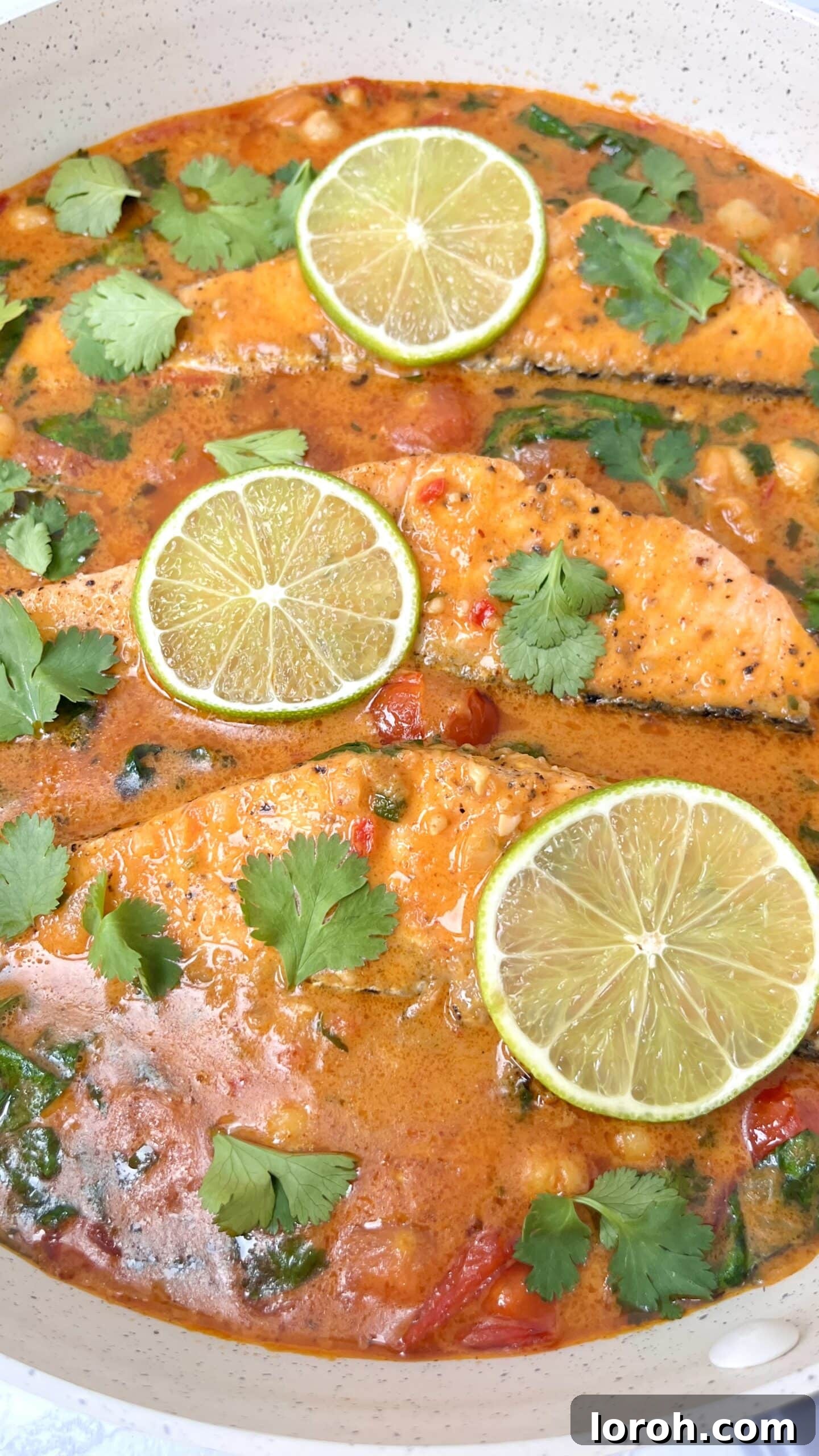 Close-up of the creamy Thai Salmon Curry with chickpeas and spinach in a pan.