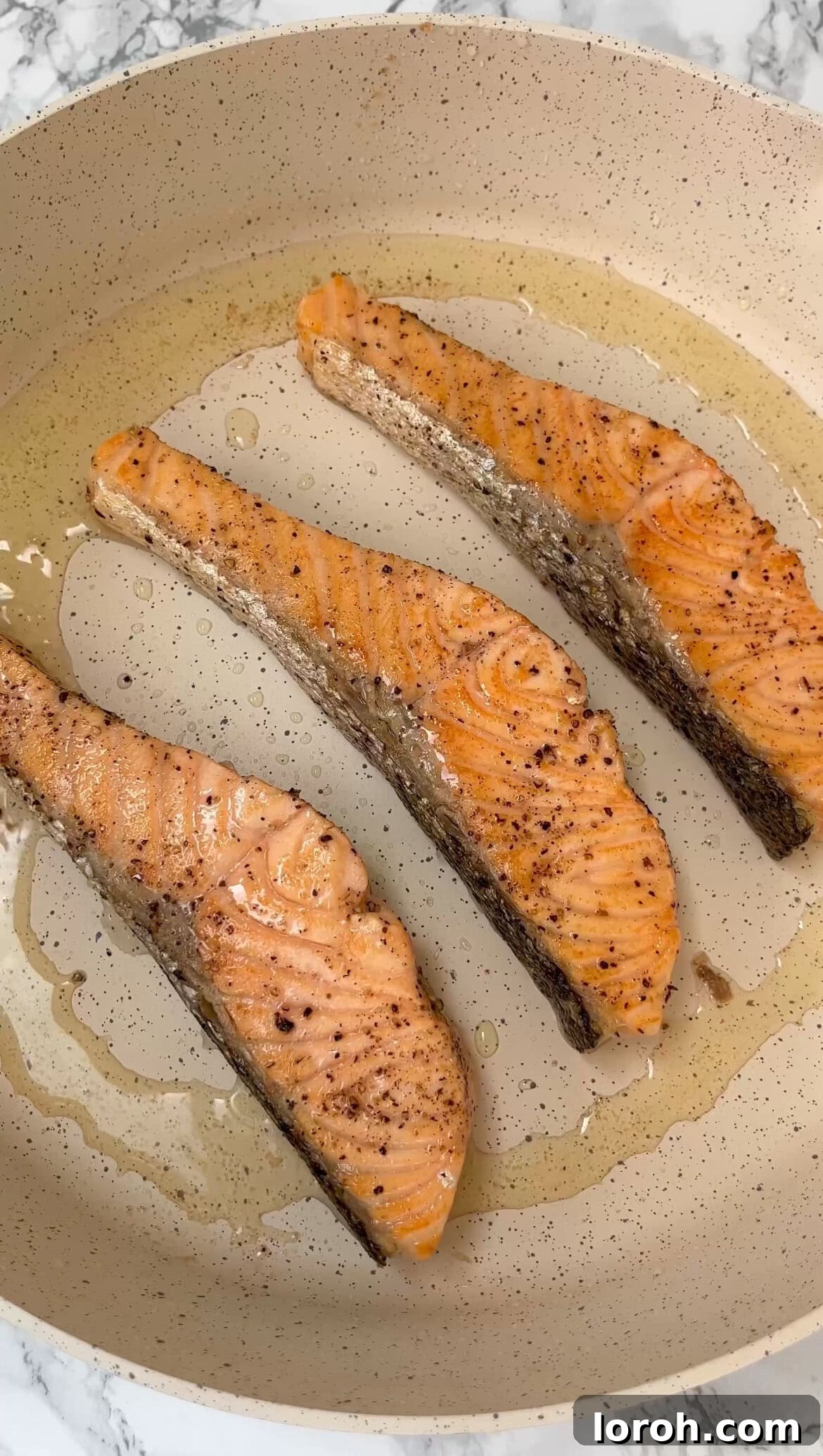 Searing salmon fillets in a hot pan until golden brown on all sides.