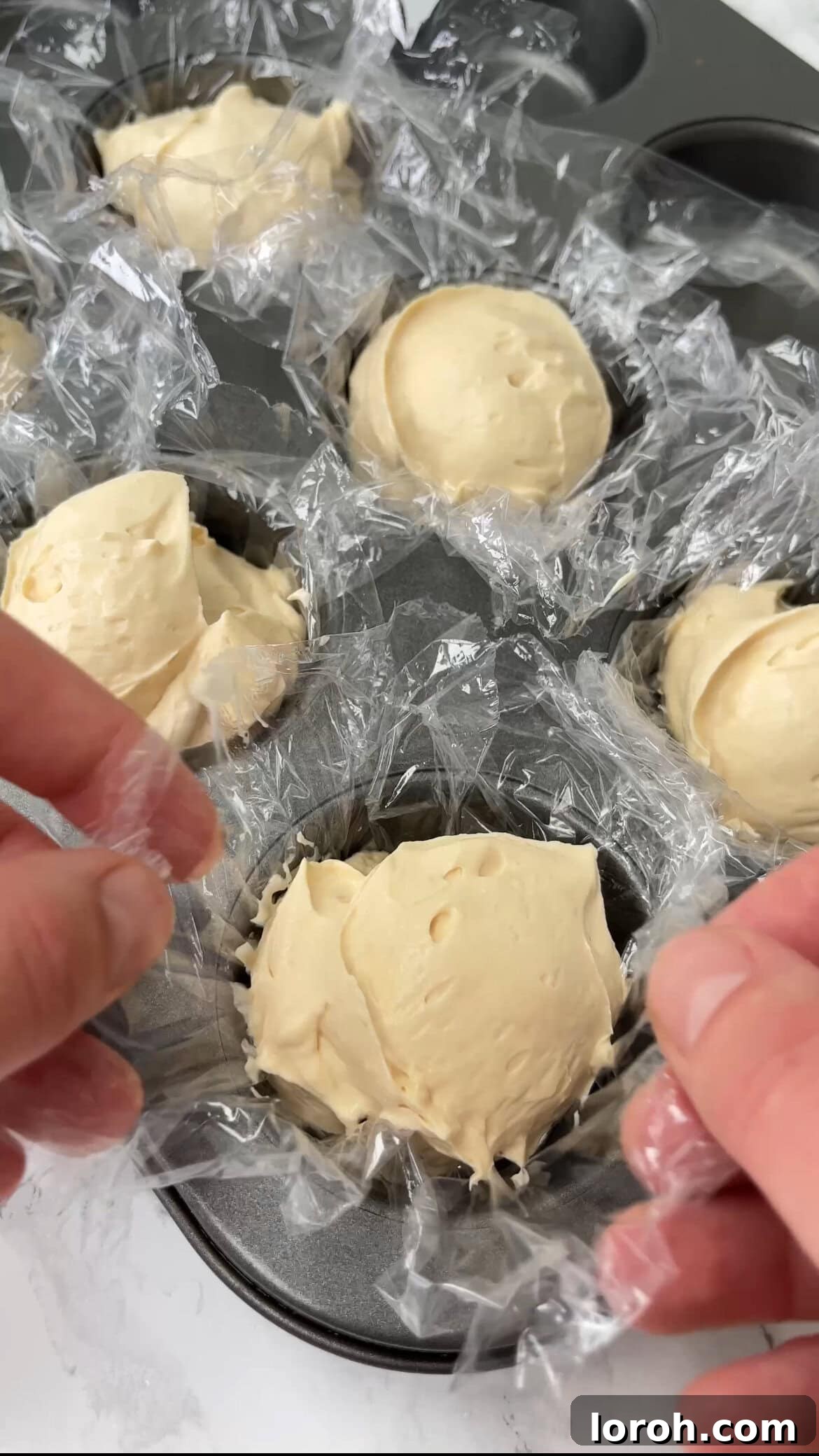 Scooping small balls of ice cream onto a parchment-lined baking tray for freezing.