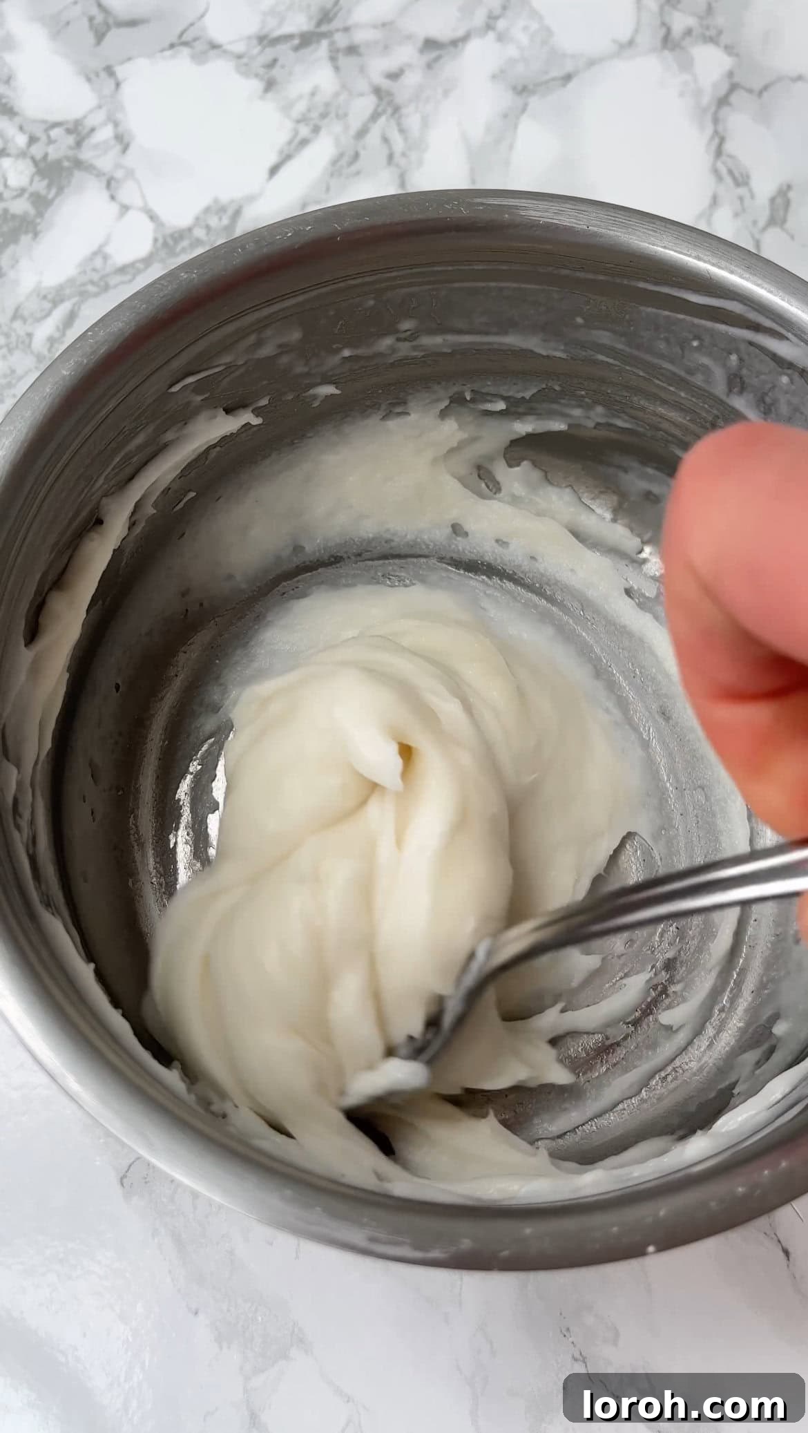 Stirring the mochi dough mixture in a saucepan as it thickens and becomes translucent.
