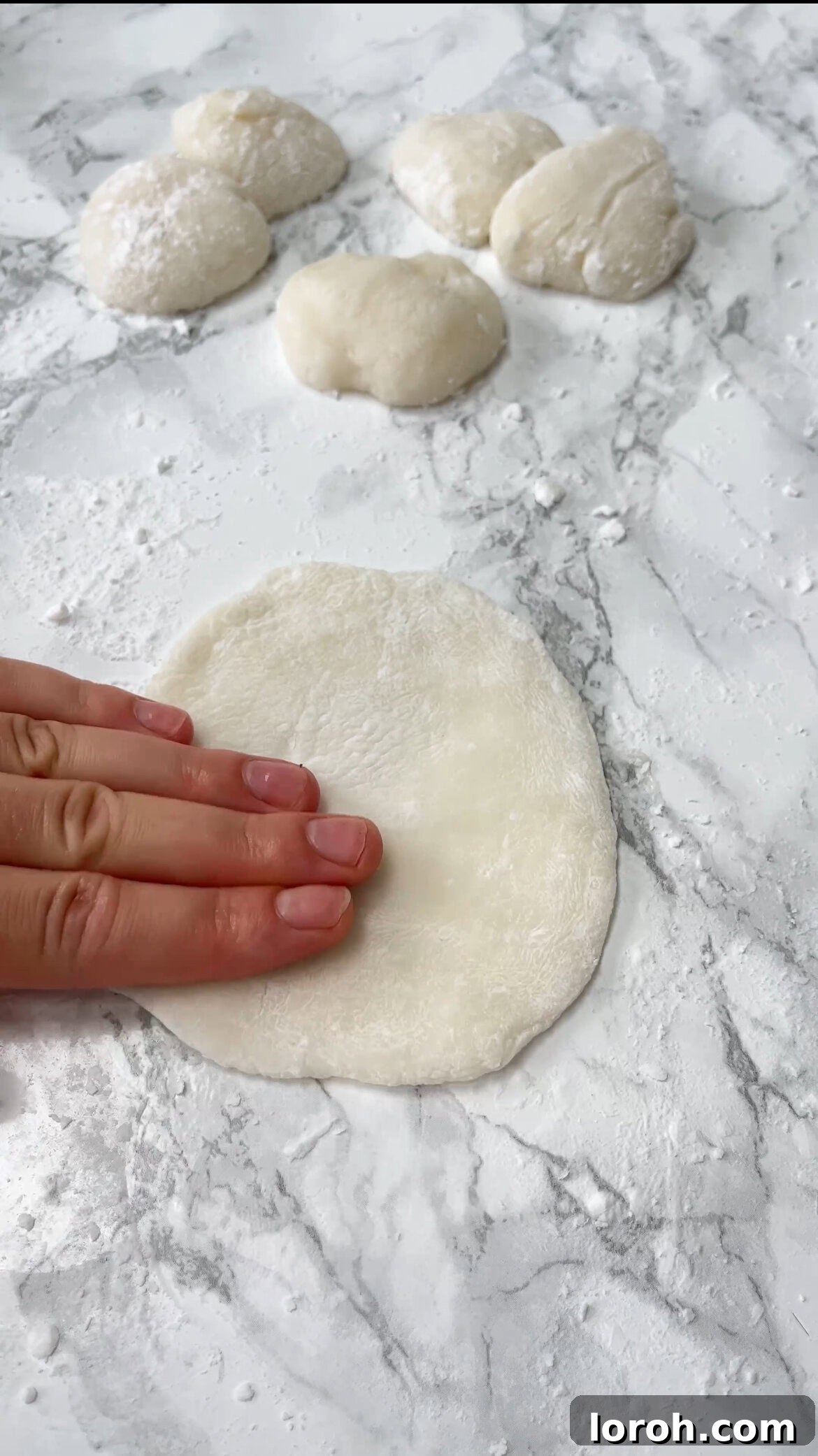 Patting out warm mochi dough on a cornstarch-dusted surface.