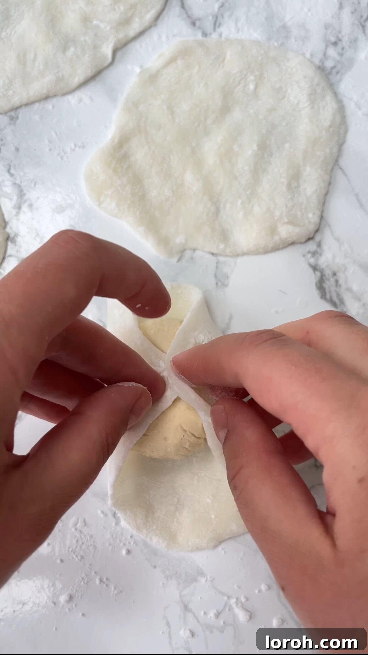 Wrapping a frozen ice cream ball inside a flattened mochi dough disc.