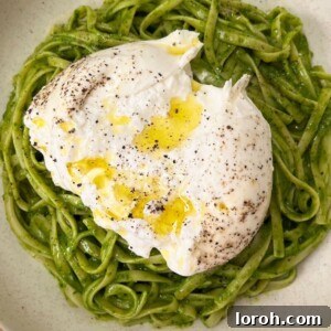 A vibrant bowl of very green pasta, brimming with fresh vegetables and herbs, beautifully plated and ready to be enjoyed. Highlighted by its rich, verdant hue.