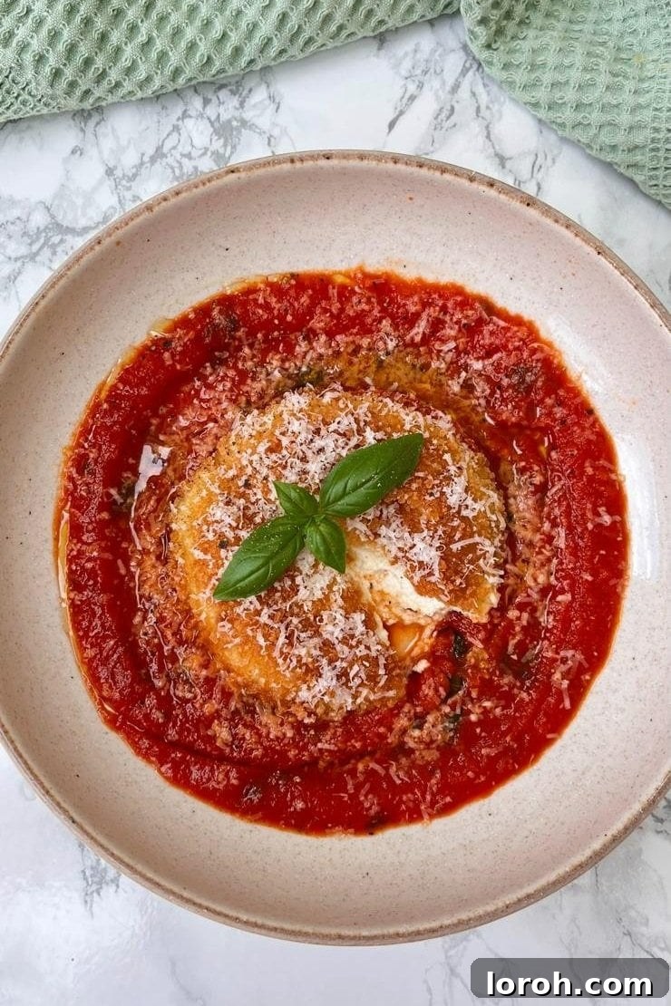 Crispy Melty Mozzarella Pockets 2 Mozzarella in Carrozza served on a bed of rich tomato sauce, presented on an elegant beige plate.