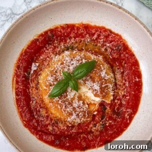 Mozzarella in Carrozza served on a bed of rich tomato sauce, presented on an elegant beige plate.