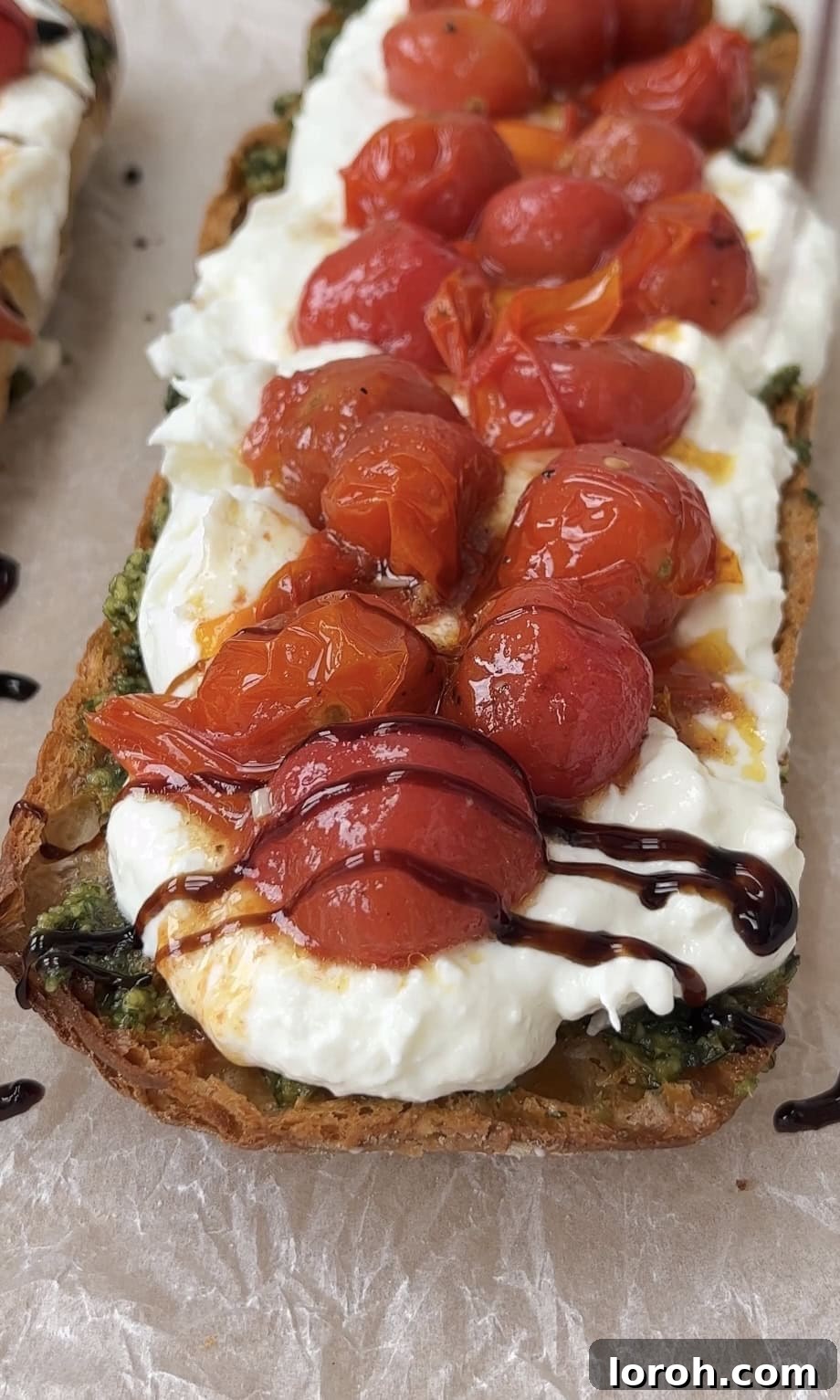 Finished Caprese bruschetta drizzled with balsamic glaze and garnished with fresh basil sprigs.