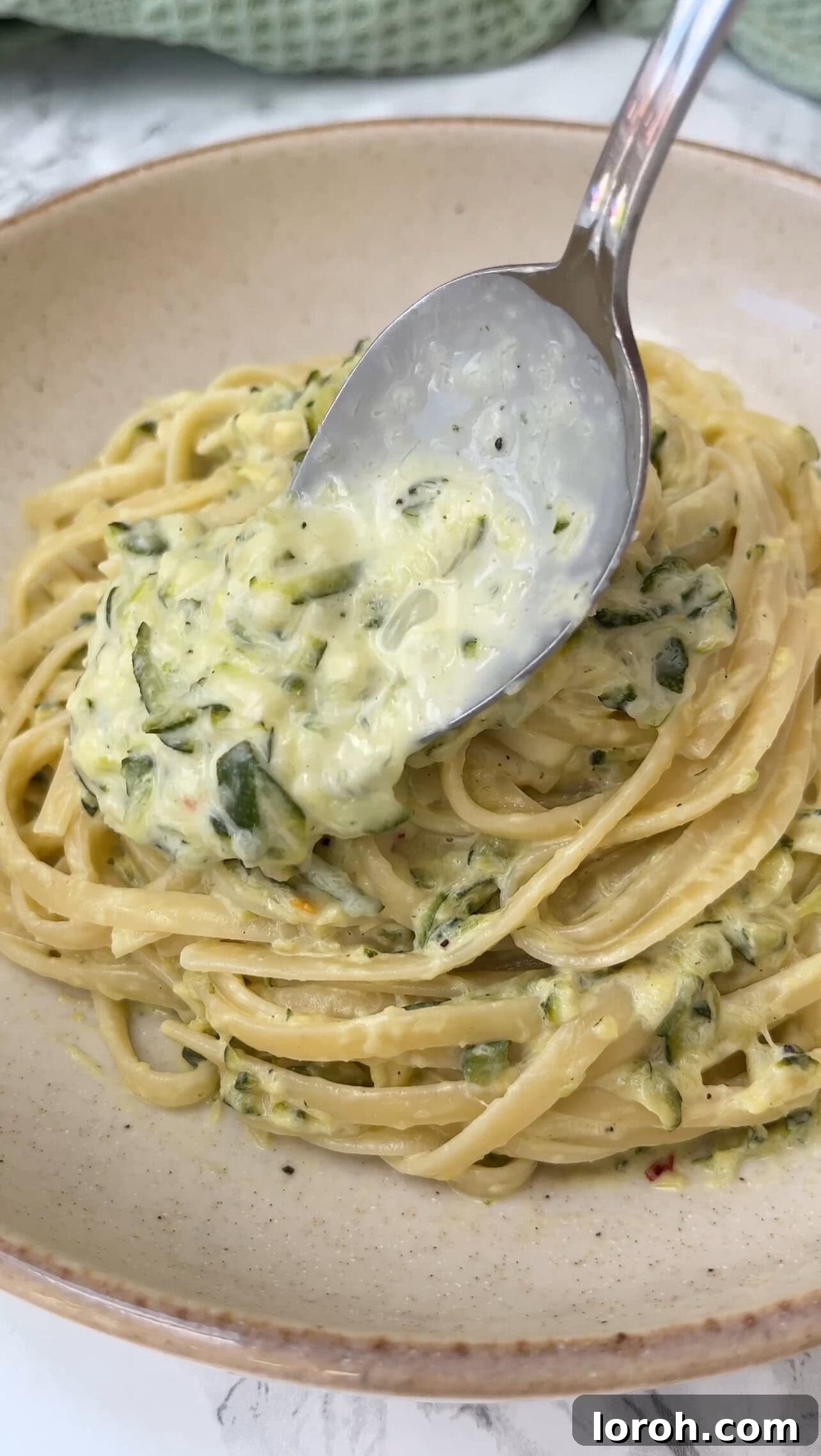 A vibrant bowl of creamy courgette pasta, garnished with fresh herbs and a sprinkle of parmesan, ready to be enjoyed.
