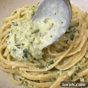 A spoon scooping creamy courgette pasta, demonstrating the rich sauce and perfectly cooked linguine.