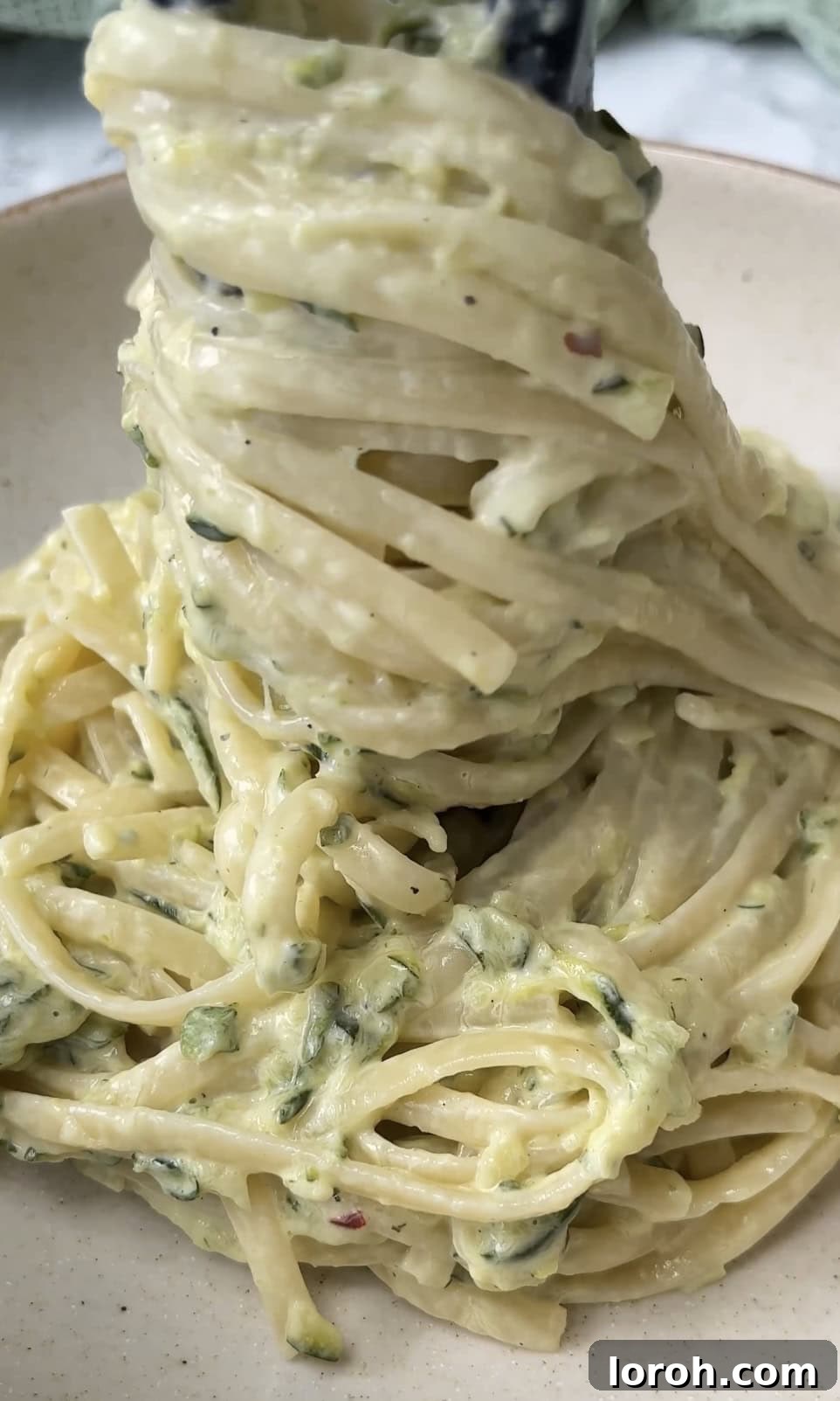 The finished creamy courgette pasta being scooped into a serving bowl, ready for a final garnish.