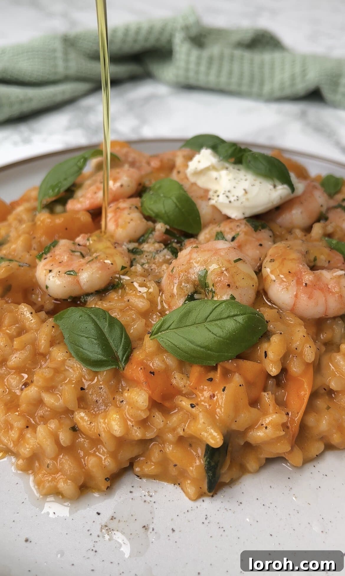 Serving creamy tomato mascarpone risotto topped with garlic prawns, basil, and olive oil drizzle.